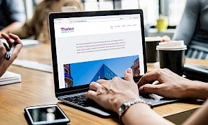 Frau navigiert auf Macbook durch die neue Tholen-Website