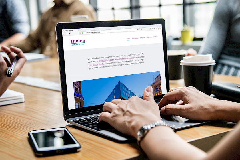Frau navigiert auf Macbook durch die neue Tholen-Website